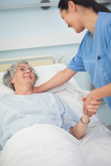 Patient smiling to a nurse while holding her hand