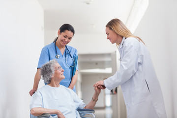 Fototapeta premium Patient in a wheelchair holding hand of a doctor