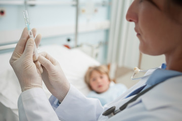 Obraz premium Doctor preparing a syringe next to a child