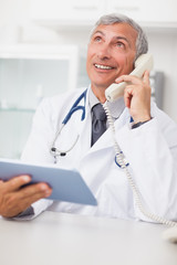 Doctor calling while holding a tablet computer