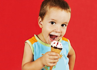 Happy boy with ice cream cone on red background.