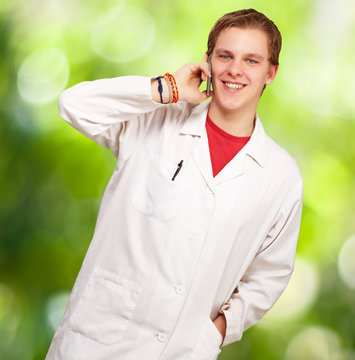 portrait of young academic talking on mobile against a nature ba