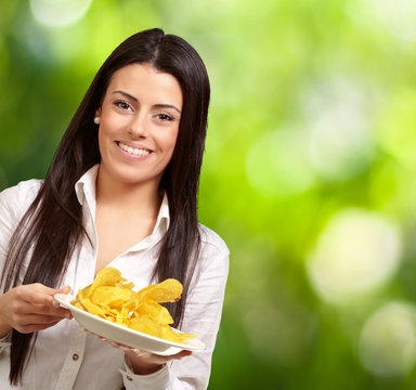 portrait of young woman holding a potato chips plate against a n