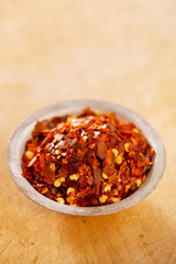 Hot Red Chilli Chillies pepper crushed in tin bowl on wood