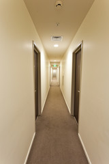 Long corridor with hotel room doors and exit sign