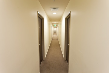 Long corridor with hotel room doors and exit sign