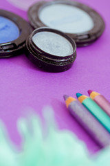 Obraz na płótnie Canvas eyepencils and eyeshadows on purple with petals