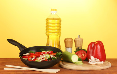 frying pan with vegetables on yellow background
