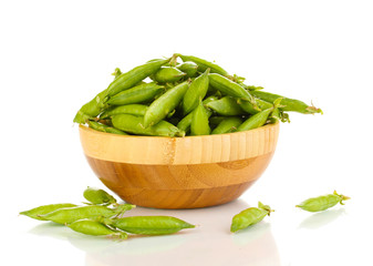 Green peas in wooden bowl isolated on white