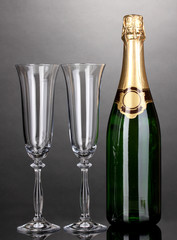 Bottle of champagne and goblets on grey background