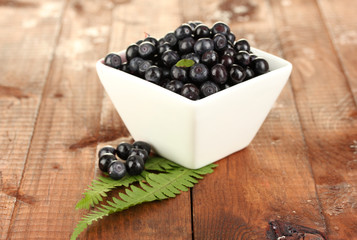 fresh blueberries in white bowl on wooden background close-up