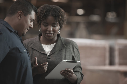 Businesswoman talking to worker in warehouse