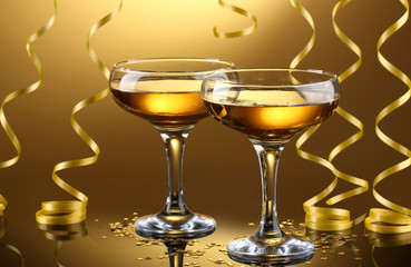 glasses of champagne and streamer on yellow background