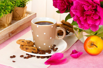 cup of coffee, cookies, apple and flowers on table in cafe