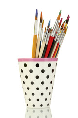 Paint brushes with gouache in cup isolated on white