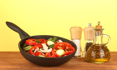 frying pan with vegetables on yellow background