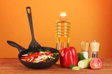 frying pan with vegetables on red background