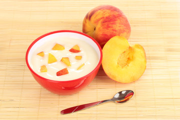 Yoghurt with peach in bowl on bamboo mat