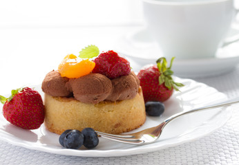 Fresh fruit tart with fork and coffee cup on background