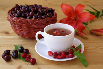 Tea with ripe strawberries and cherry