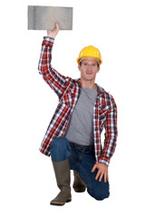 portrait of bricklayer holding block of concrete