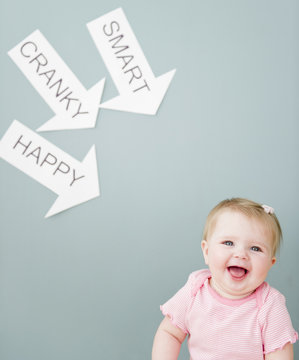 Caucasian baby near arrows reading cranky, smart and happy