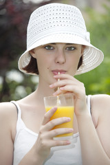 young girl drinking  orange juice in the garden