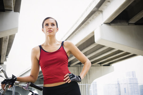 Hispanic woman standing in urban area with bicycle