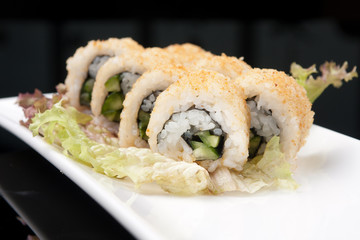 sushi rolls on a white plate over black background