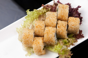 sushi rolls on a white plate over black background