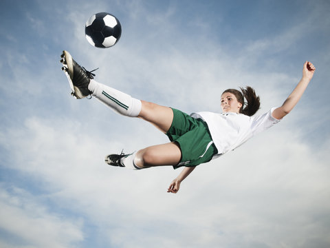 Caucasian Teenager Kicking Soccer Ball In Mid-air