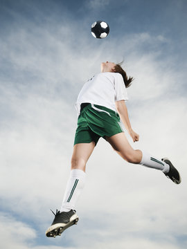 Caucasian teenager heading soccer ball in mid-air