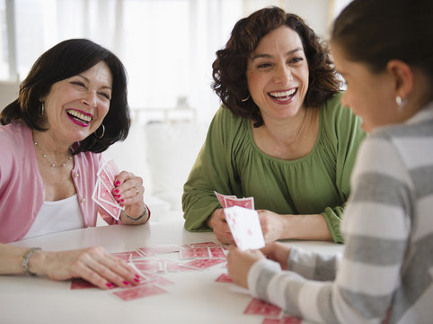 Grandmother, mother and daughter playing cards