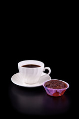 Hot cup of coffee and chocolate cherry muffin on black