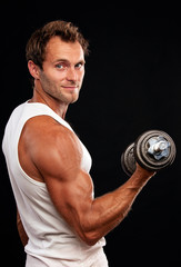 Fototapeta na wymiar Muscular man lifting dumbbell on black background