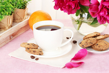 cup of coffee, cookies, orange and flowers on table in cafe