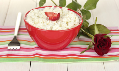 cottage cheese with strawberry in red bowl, fork and flower