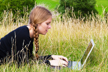 Junge Frau mit Laptop auf der Wiese