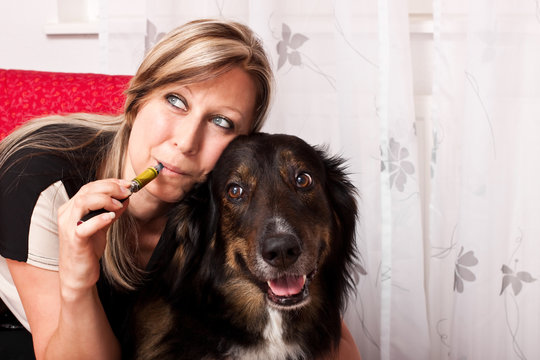 Junge blonde Frau mit Mischlings Hund dampft E Zigarette