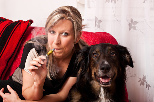 Blonde Frau mit Hund und elektrischer Zigarette