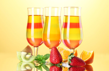 fruit jelly in glasses and fruits on yellow background