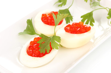 Red caviar in eggs on white plate isolated on white