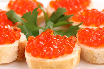 Red caviar on bread on white plate close-up