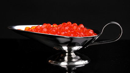 Red caviar in silver bowl isolated on black