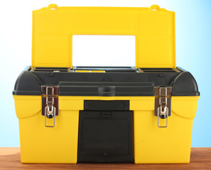 Open yellow tool box on blue background close-up