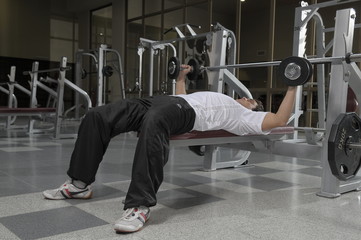 Hombre joven haciendo gimnasia, levantando pesas