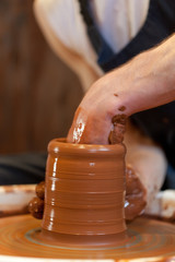 hands of a potter, creating an earthen jar on the circle