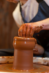 hands of a potter, creating an earthen jar on the circle
