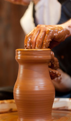 hands of a potter, creating an earthen jar on the circle