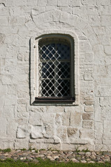 Окно с решеткой на старинной каменной стене.